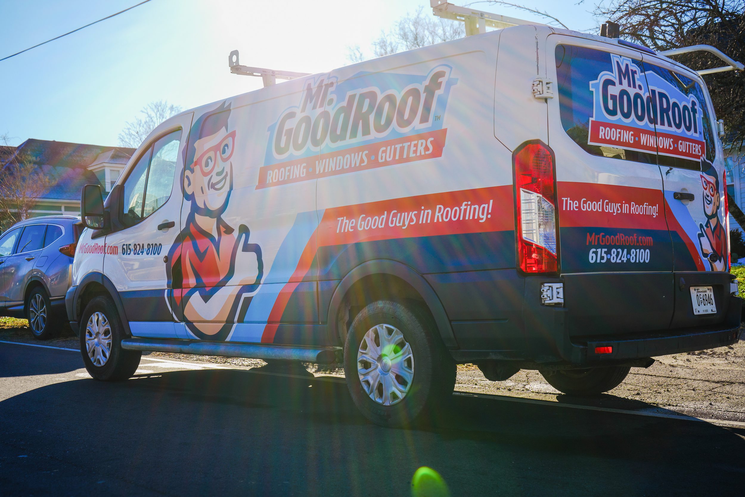 A white van covered in graphics for Mr Goodroof roofing company